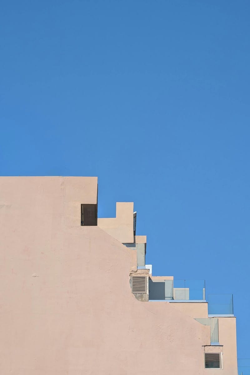 Minimalist architectural shot of a modern building facade in Rethymno, Greece with clear blue sky backdrop.