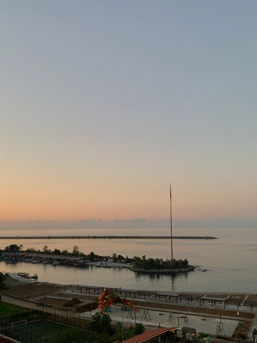 Free A tranquil view of a coastal area during sunset, featuring calm waters and gentle pastel skies. Stock Photo
