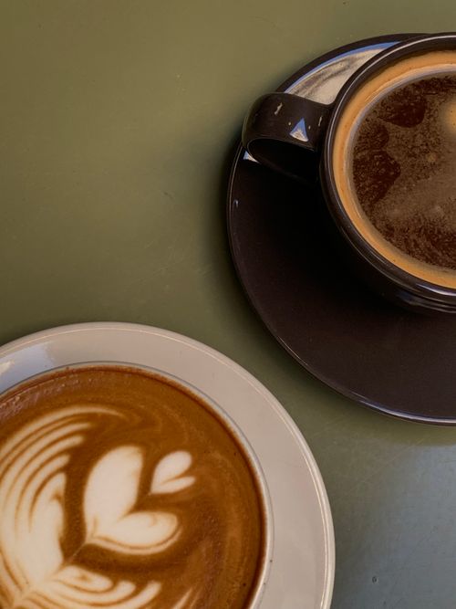 Free Two coffee cups on a table, one with elegant latte art, perfect for cafe ambiance. Stock Photo