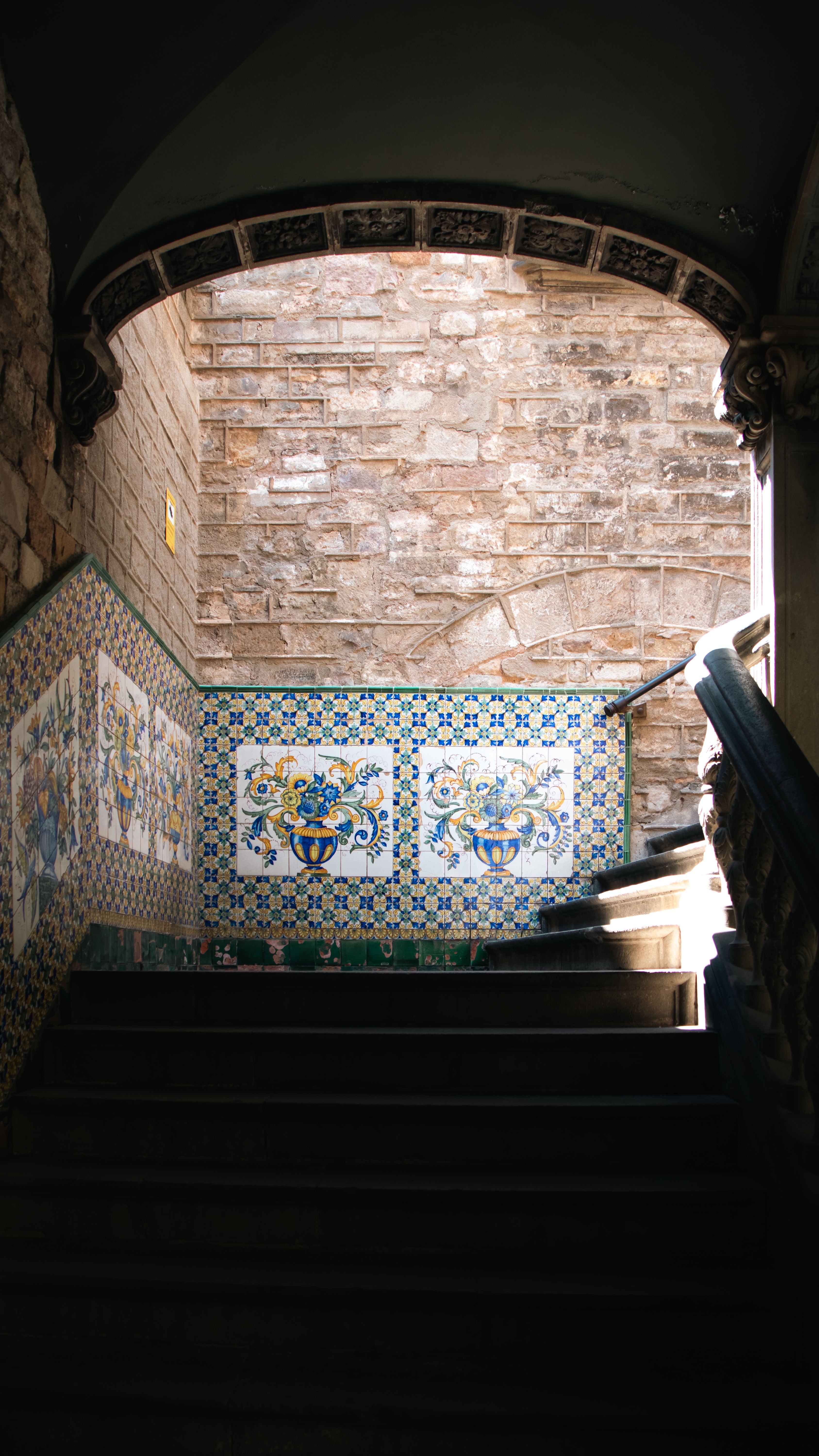 Escalier ancien à carreaux décorés Escalier d'immeuble ancien aux marches recouvertes de carreaux de faïence colorés, rampe en fer forgé