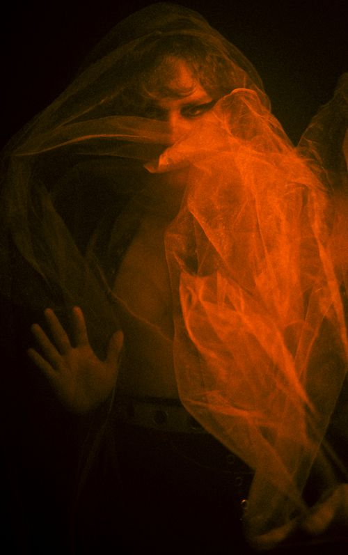 Free Artistic portrait of a person partially obscured by an orange veil, creating a mysterious and dramatic effect. Stock Photo