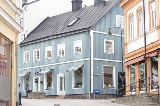 A serene Swedish street scene featuring a blue house with local shops, ideal for exploring small town charm.