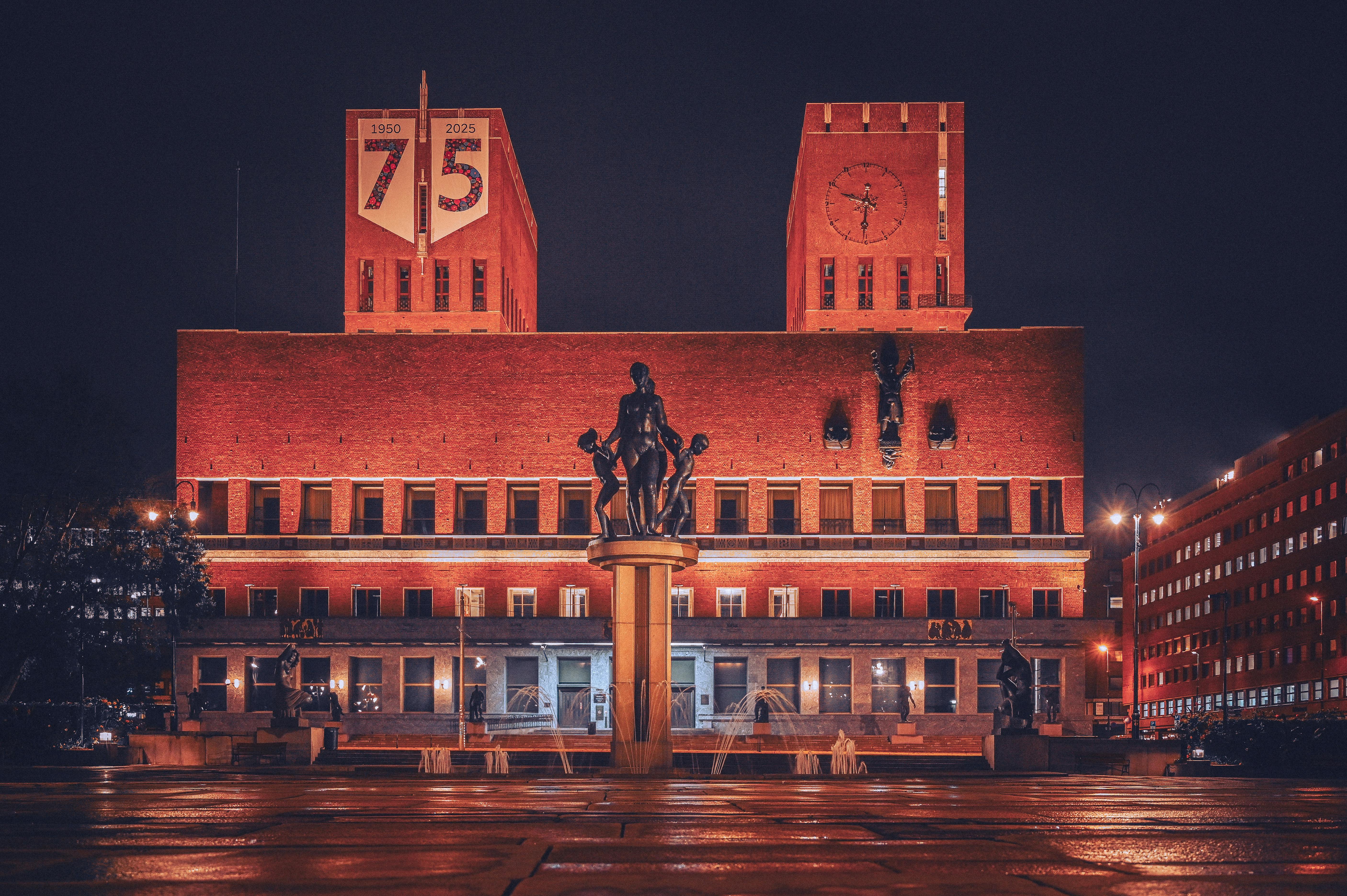 Stunning night view of Oslo City Hall with a beautifully lit statue foreground.