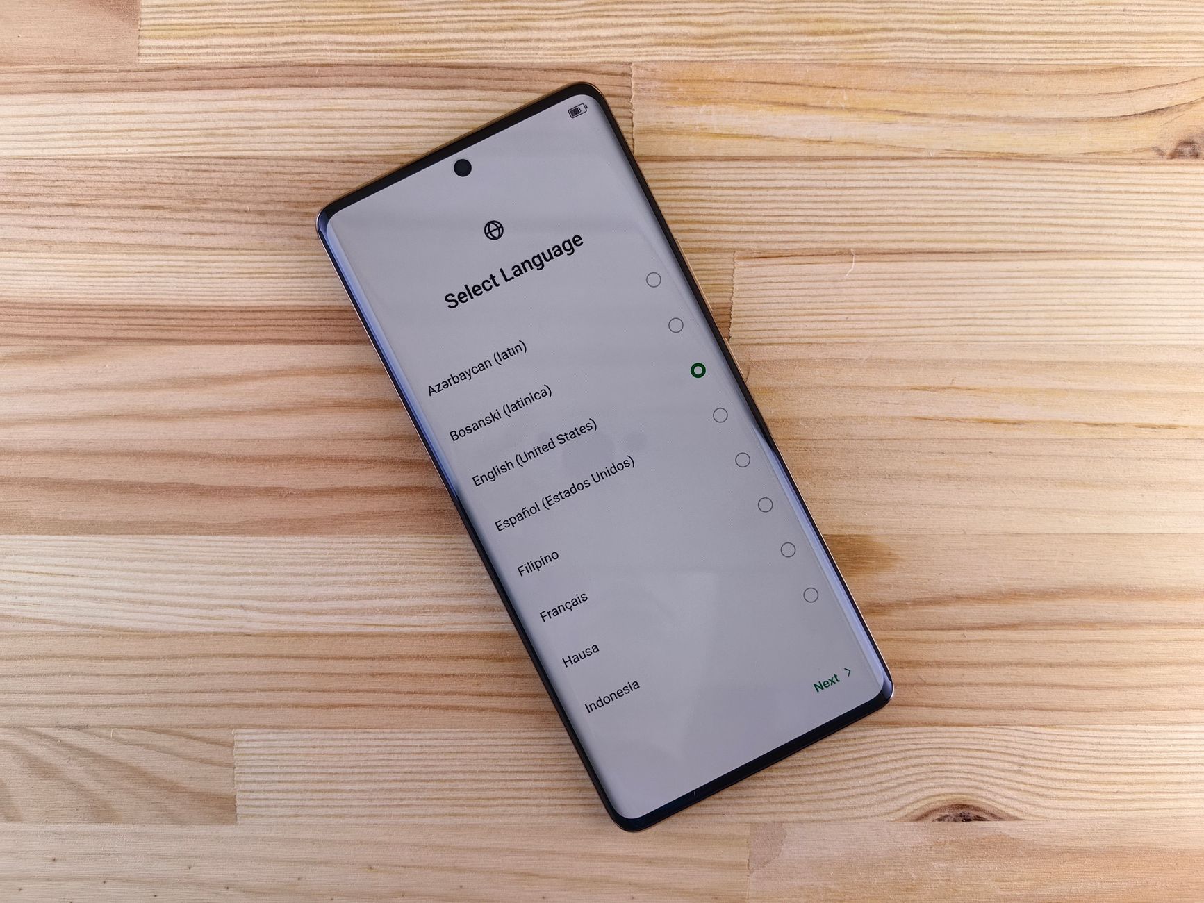 Close-up of smartphone with language selection screen on wooden table.