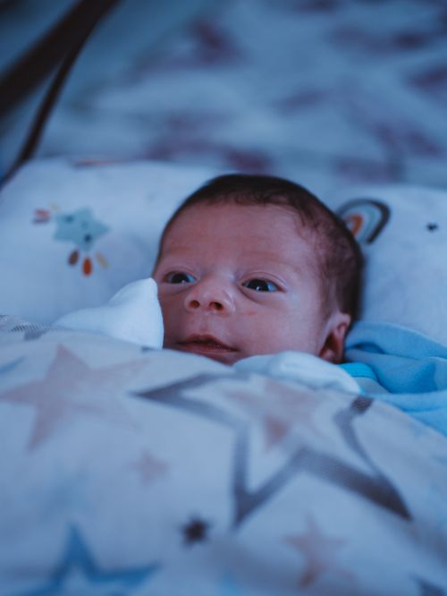 Free A cute baby wrapped in a cozy star-patterned blanket, peacefully resting. Stock Photo