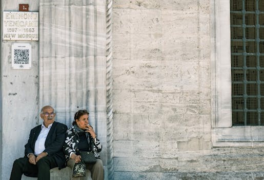 Senior couple sitting by the New Mosque in Eminönü, Istanbul, reflecting a moment of leisure.