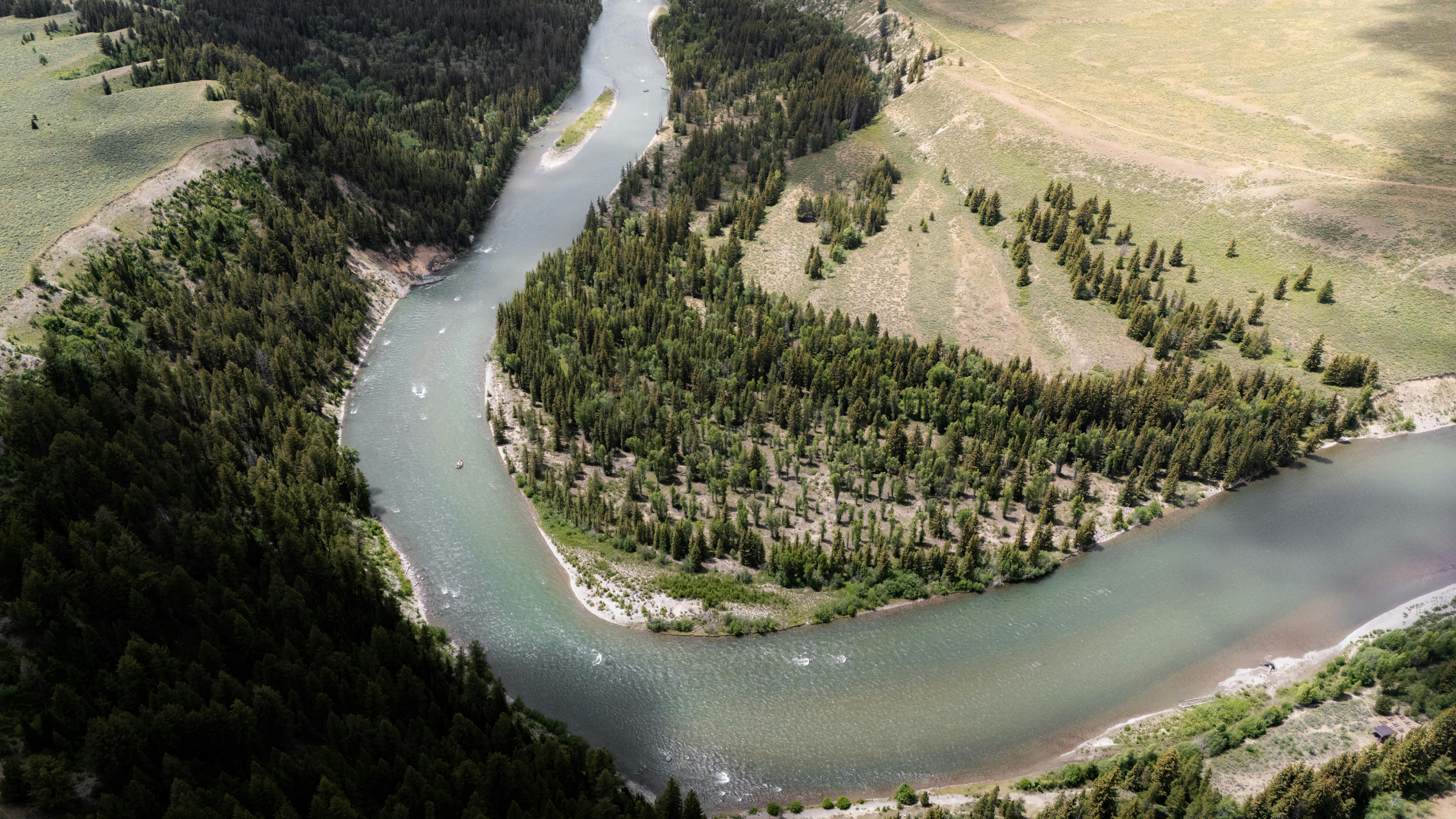 Aerial view of a serene river winding through lush forests and open fields.