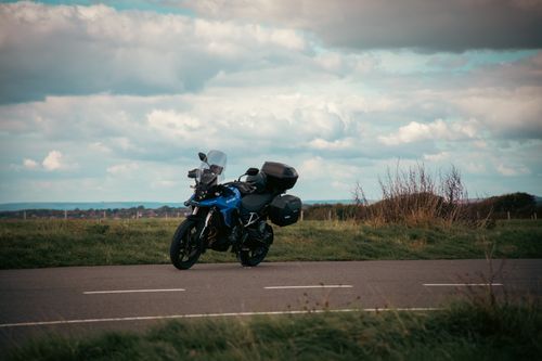 Free A blue motorcycle parked on a road in the English countryside under a cloudy sky. Stock Photo