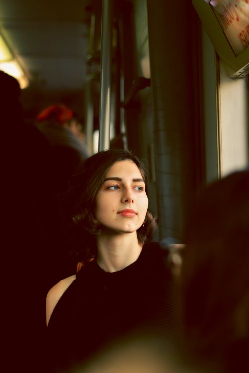 Free Portrait of a thoughtful woman looking out a train window, lost in reflection. Stock Photo