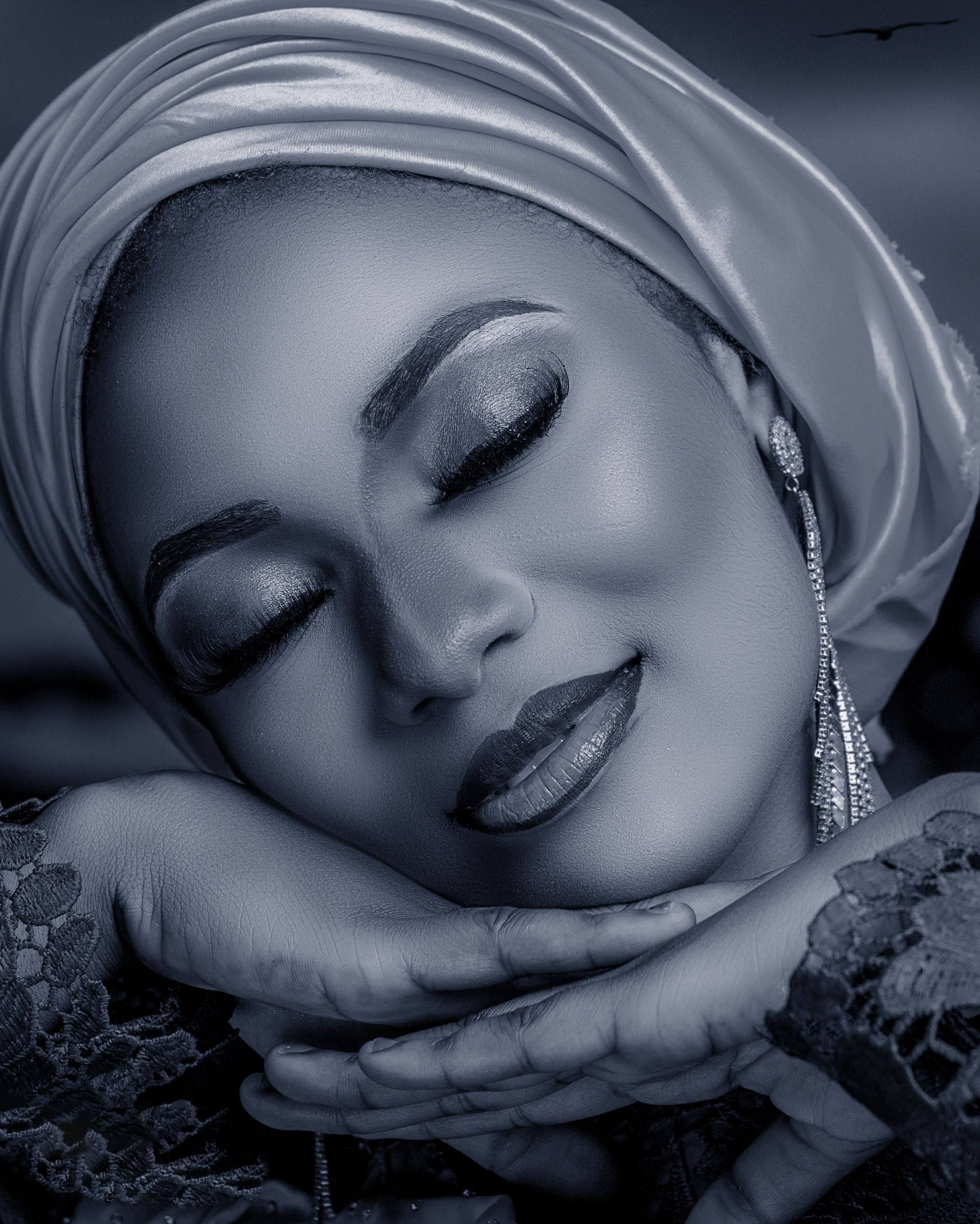 Artistic black and white portrait of a serene woman in elegant attire.