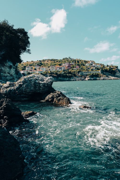 Free Picturesque view of rocky shoreline and coastal town under a blue sky. Stock Photo