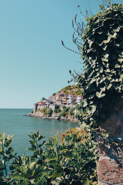 Free Picturesque Mediterranean town by the sea with lush greenery and historic architecture. Stock Photo