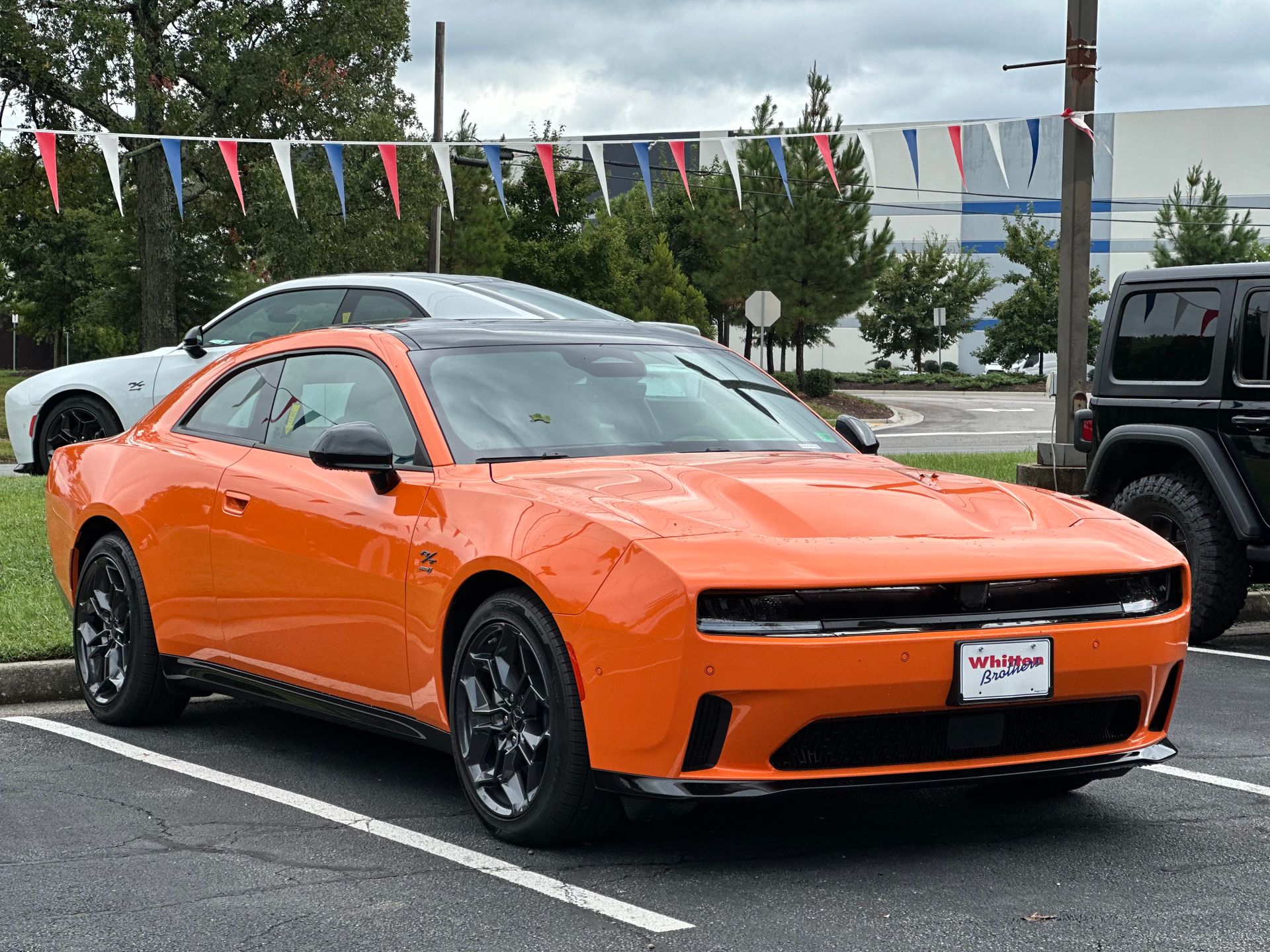 Orange sports car parked outdoors with colorful pennant flags above.