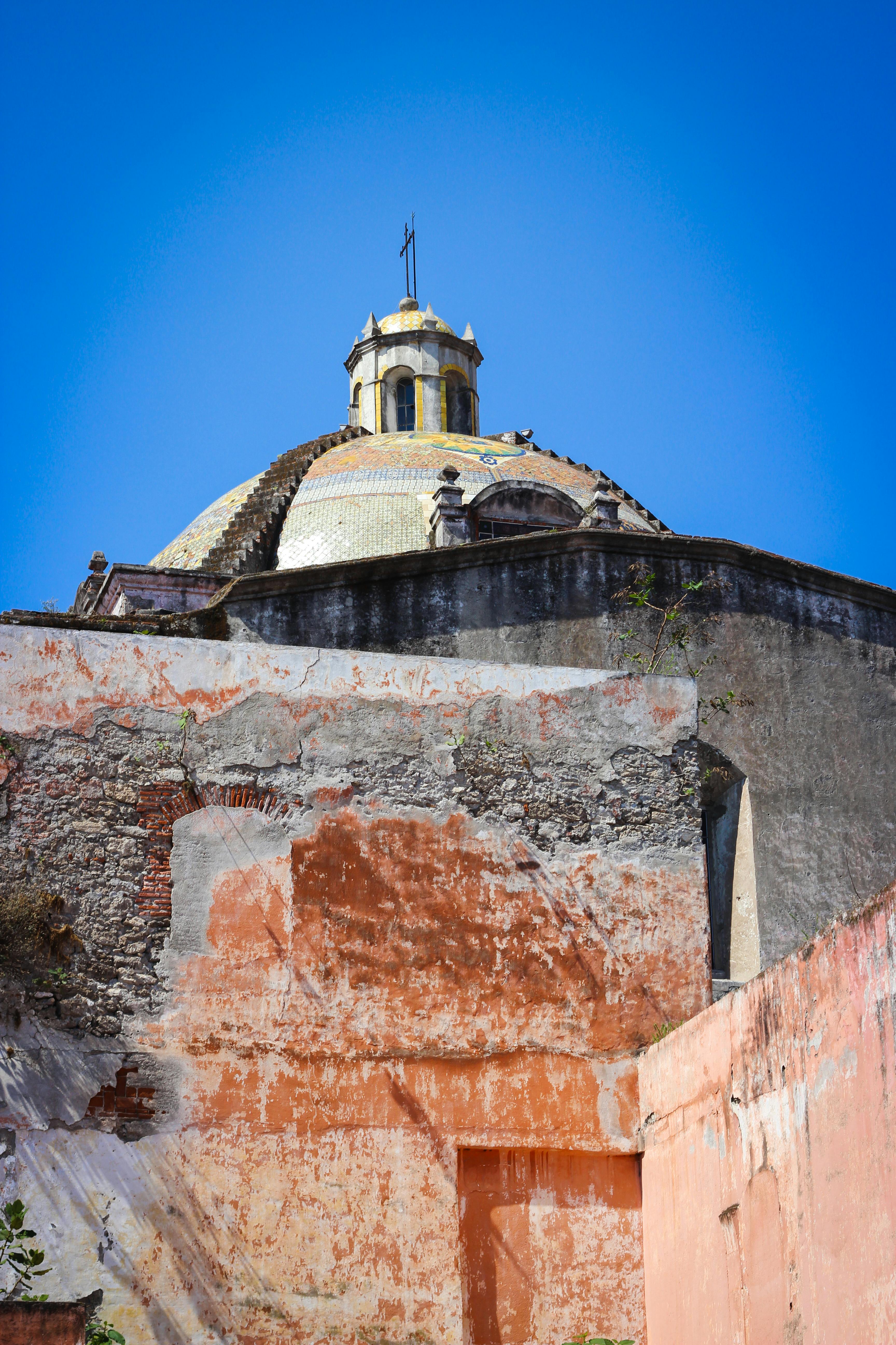 View of a historic church dome in Puebla, Mexico, showcasing classic architectural elements against a clear sky.