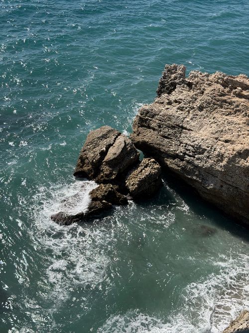 Free Dramatic view of rocky ocean cliffs with waves crashing below under bright daylight. Stock Photo