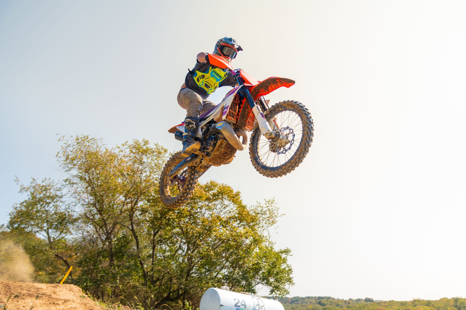 A motocross rider performs an impressive jump in an outdoor setting during daylight.