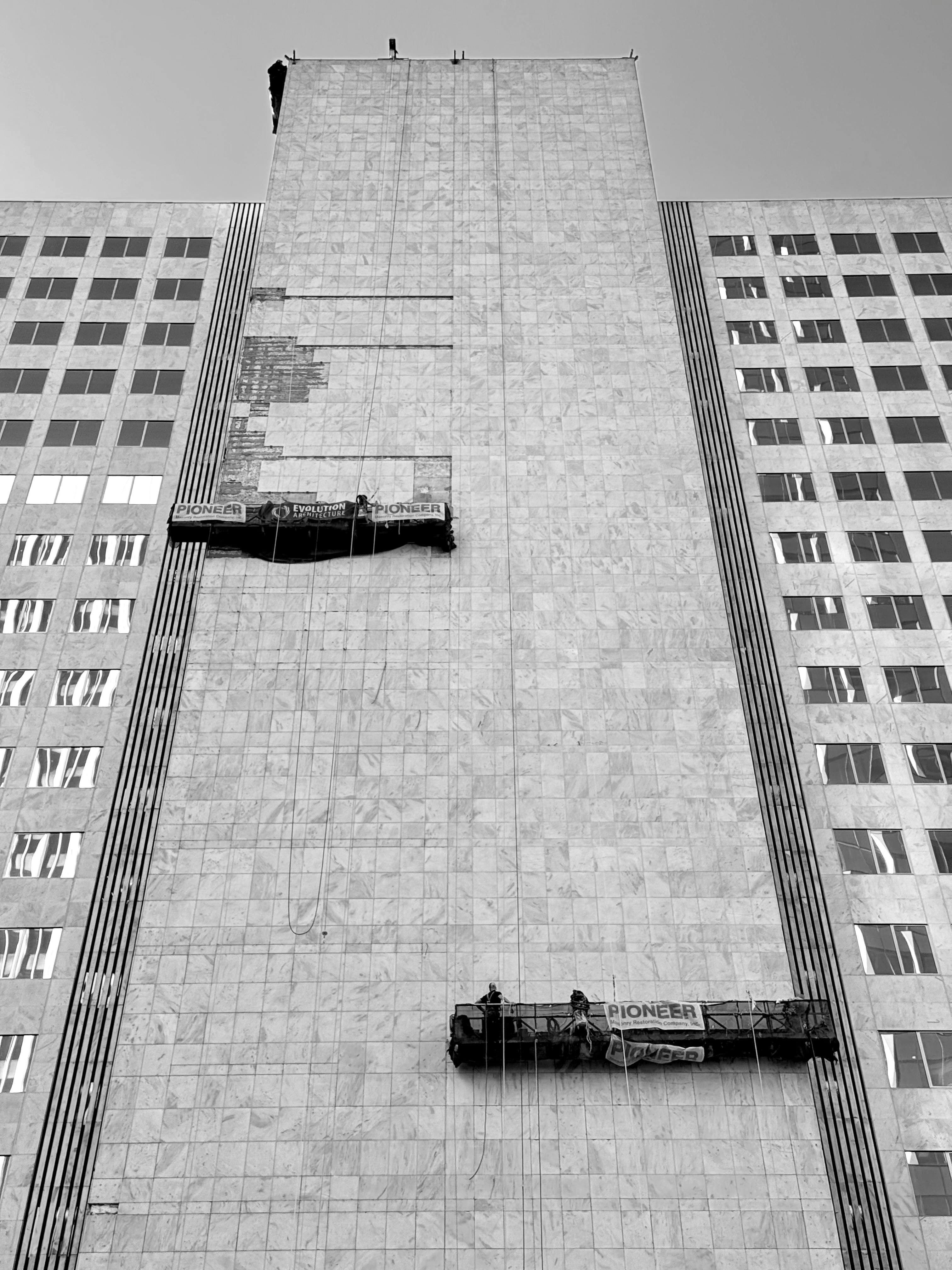 Workers repairing a high-rise building facade from suspended scaffolding