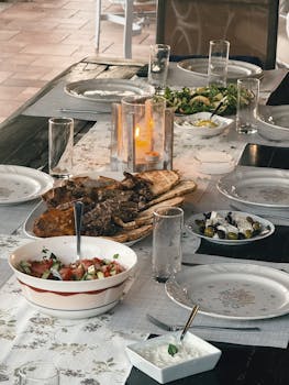 Candle-lit Mediterranean-style dinner setup with assorted dishes and elegant tableware.
