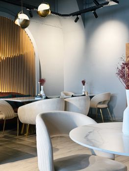 Modern cafe interior with elegant chairs, marble tables, and soft lighting for a cozy atmosphere.