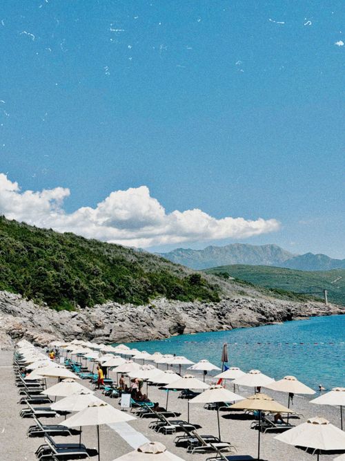 Free A sunny beach scene with umbrellas and clear sky, ideal for summer vacations. Stock Photo