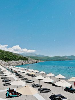 Idyllic seaside view with loungers and umbrellas under a clear blue sky.