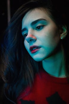 一幅带有蓝绿灯光的迷人女性肖像，唤起神秘与诱惑