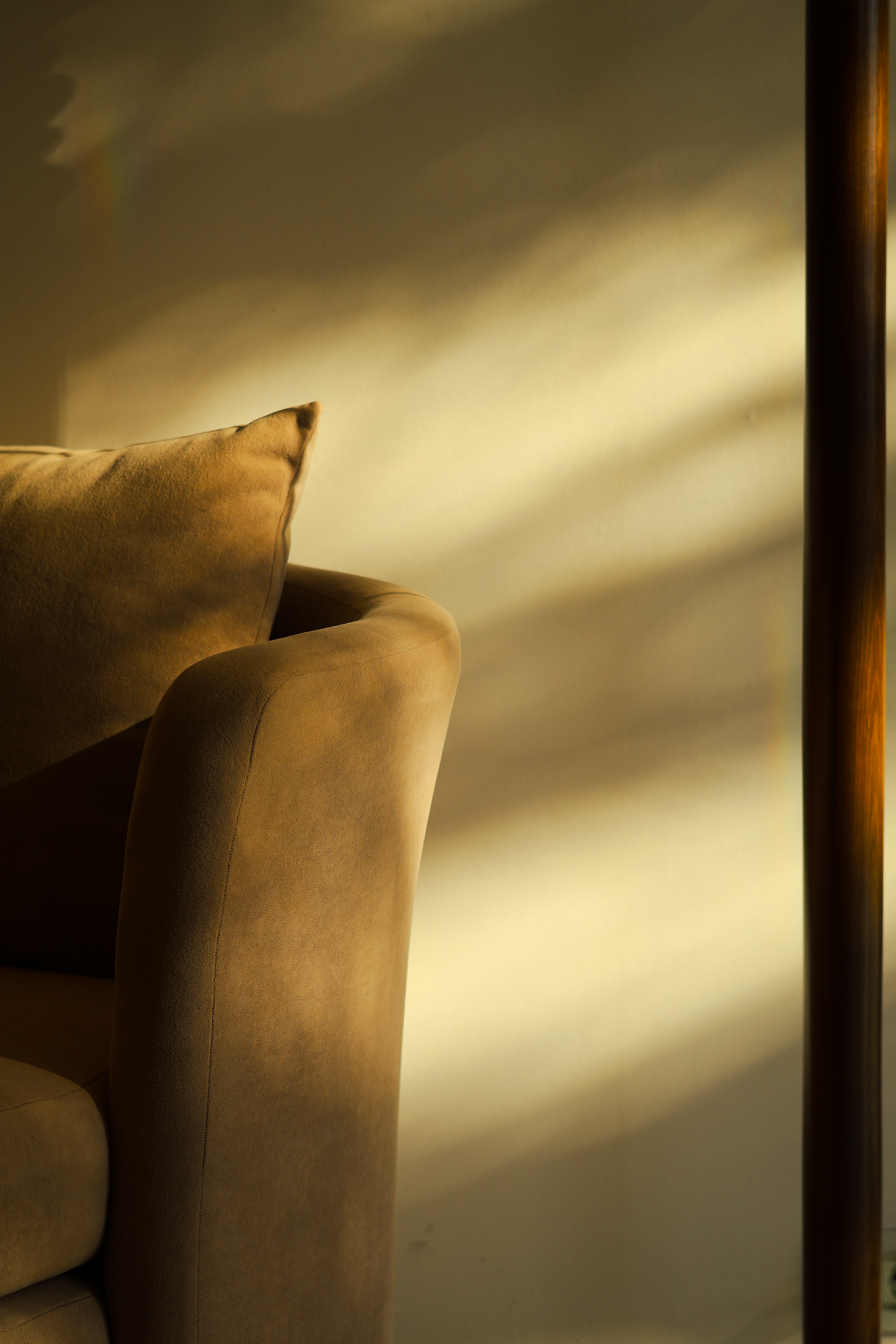 Cozy brown sofa in warm sunlight casting soft shadows indoors.