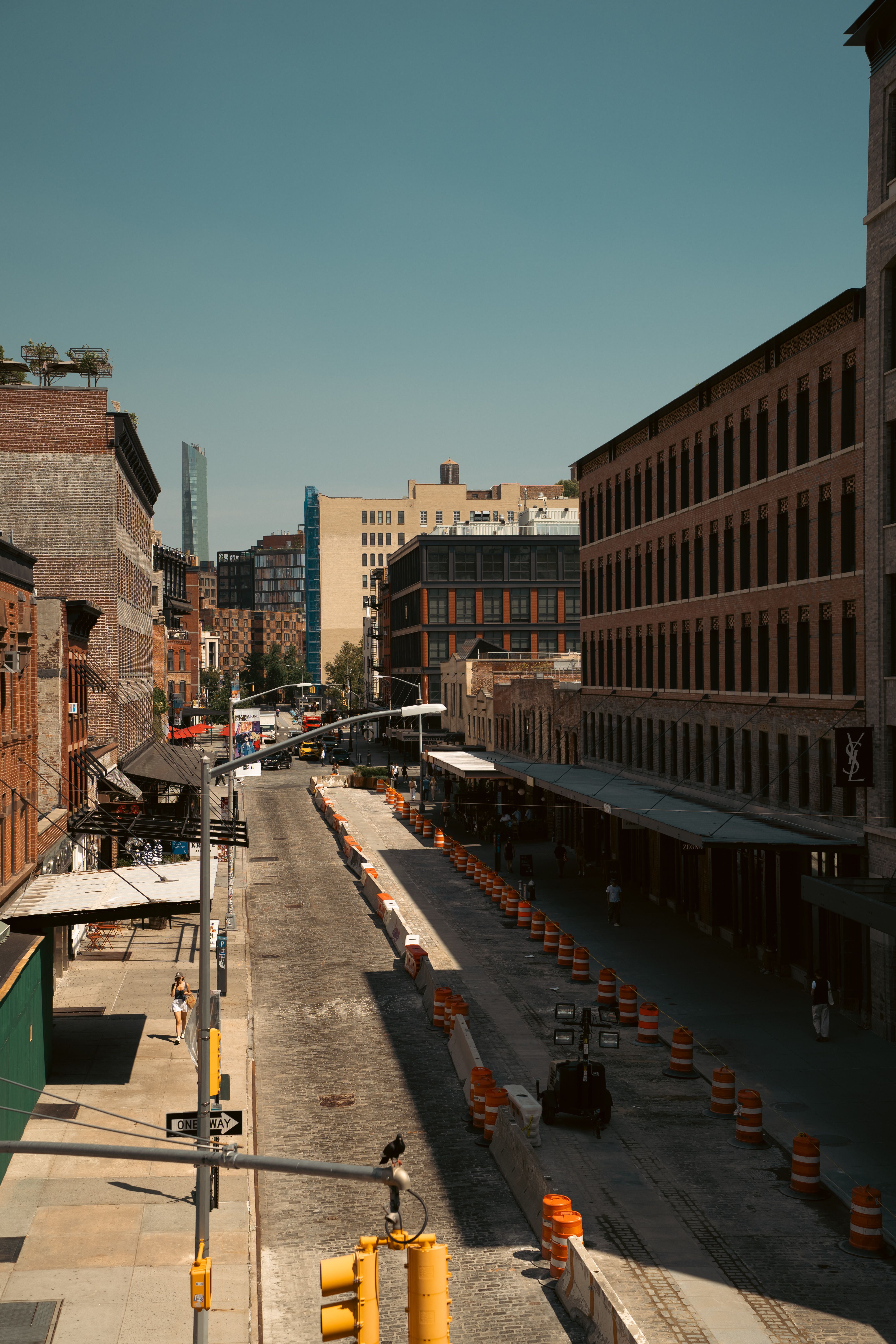 A vibrant urban street in an industrial district with construction barriers and historic architecture.
