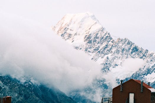 Majestic Aoraki Mount Cook in New Zealand, engulfed by clouds, offering a breathtaking snowy spectacle.