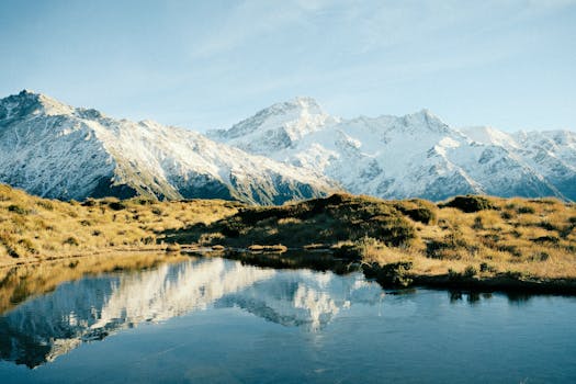 Experience the breathtaking beauty of snow-capped mountains reflecting in crystal clear waters in New Zealand.