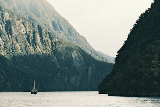 Majestic Milford Sound fjord in New Zealand with a lone boat on calm waters surrounded by towering cliffs.