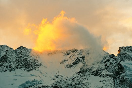 Golden sunrise illuminating snow-covered mountains in New Zealand, creating a dramatic and scenic view.