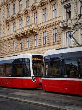 Red and white trams passing by historic architecture in Vienna, Austria. Urban transportation scene.