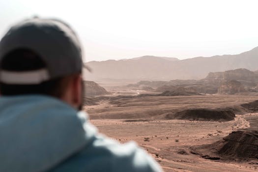 一名戴帽子的男子看到了广阔宁静的沙漠景观和岩石结构