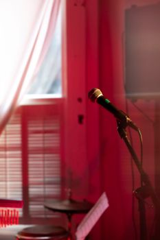 A microphone in a dimly lit studio with red lighting, creating a moody and artistic atmosphere.