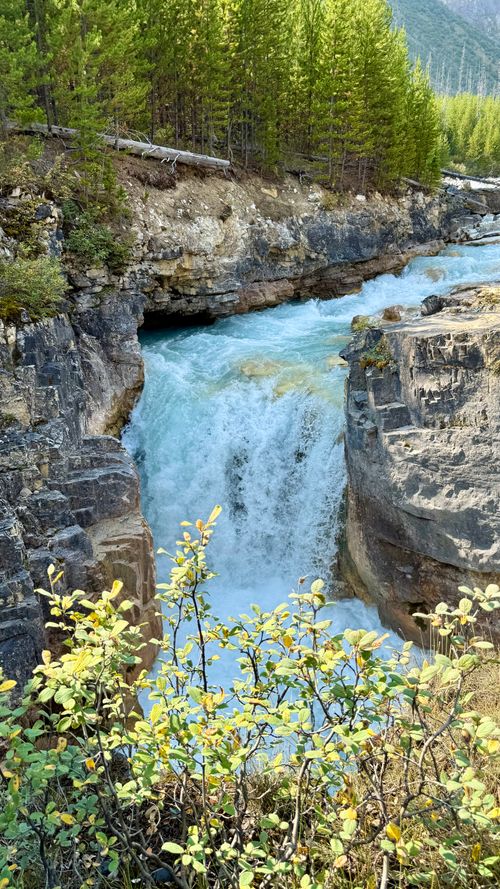 Free A stunning waterfall cascading through rocky terrain surrounded by lush greenery. Stock Photo