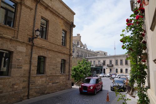 Free A vibrant street scene with a red taxi and historic architecture near Baku TV Tower in Azerbaijan. Stock Photo