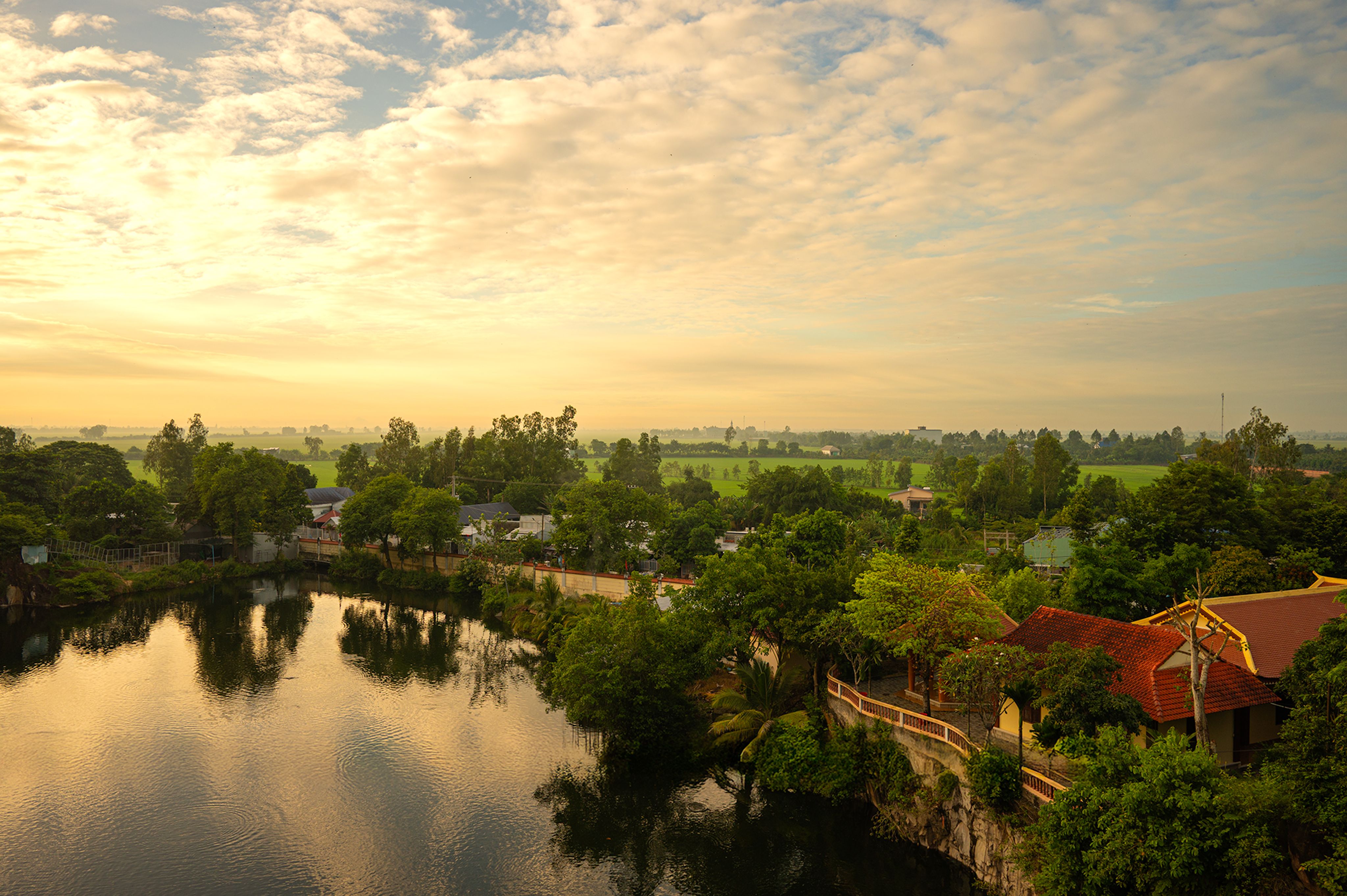 Captivating sunrise over a serene village in An Giang, Vietnam, reflecting the peaceful rural landscape.