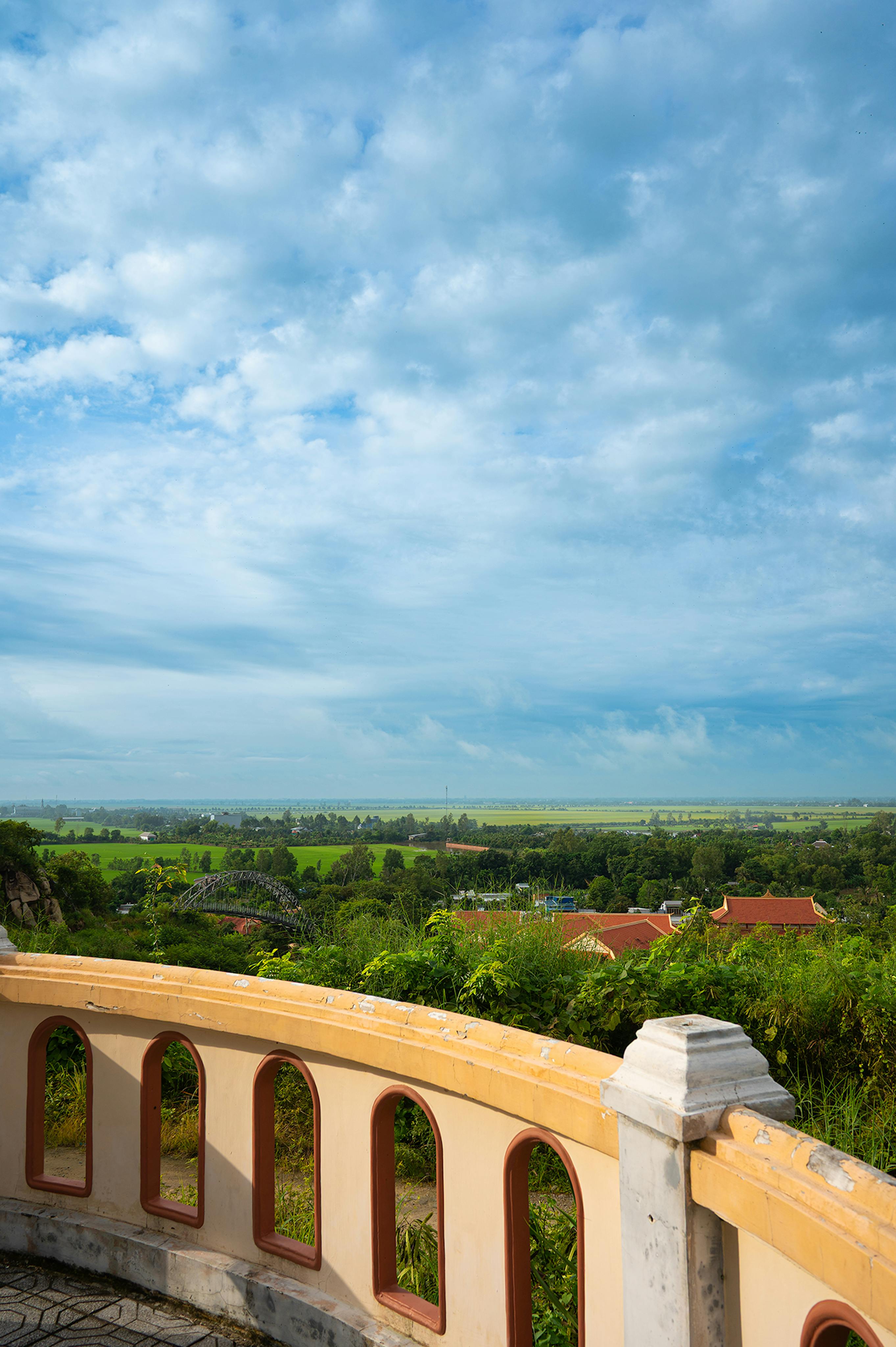 Serene landscape view from Sam Mountain overlooking lush greenery and open sky in An Giang, Vietnam.