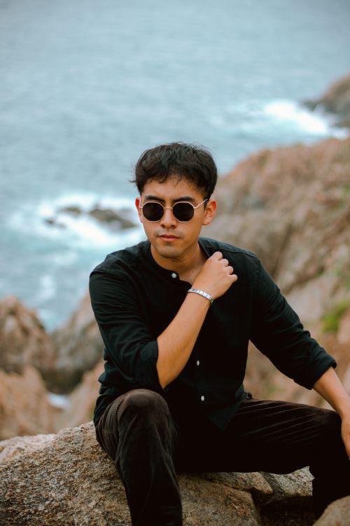 Free Portrait of a fashionable young man with sunglasses by the ocean in Santa María Huatulco, Mexico. Stock Photo