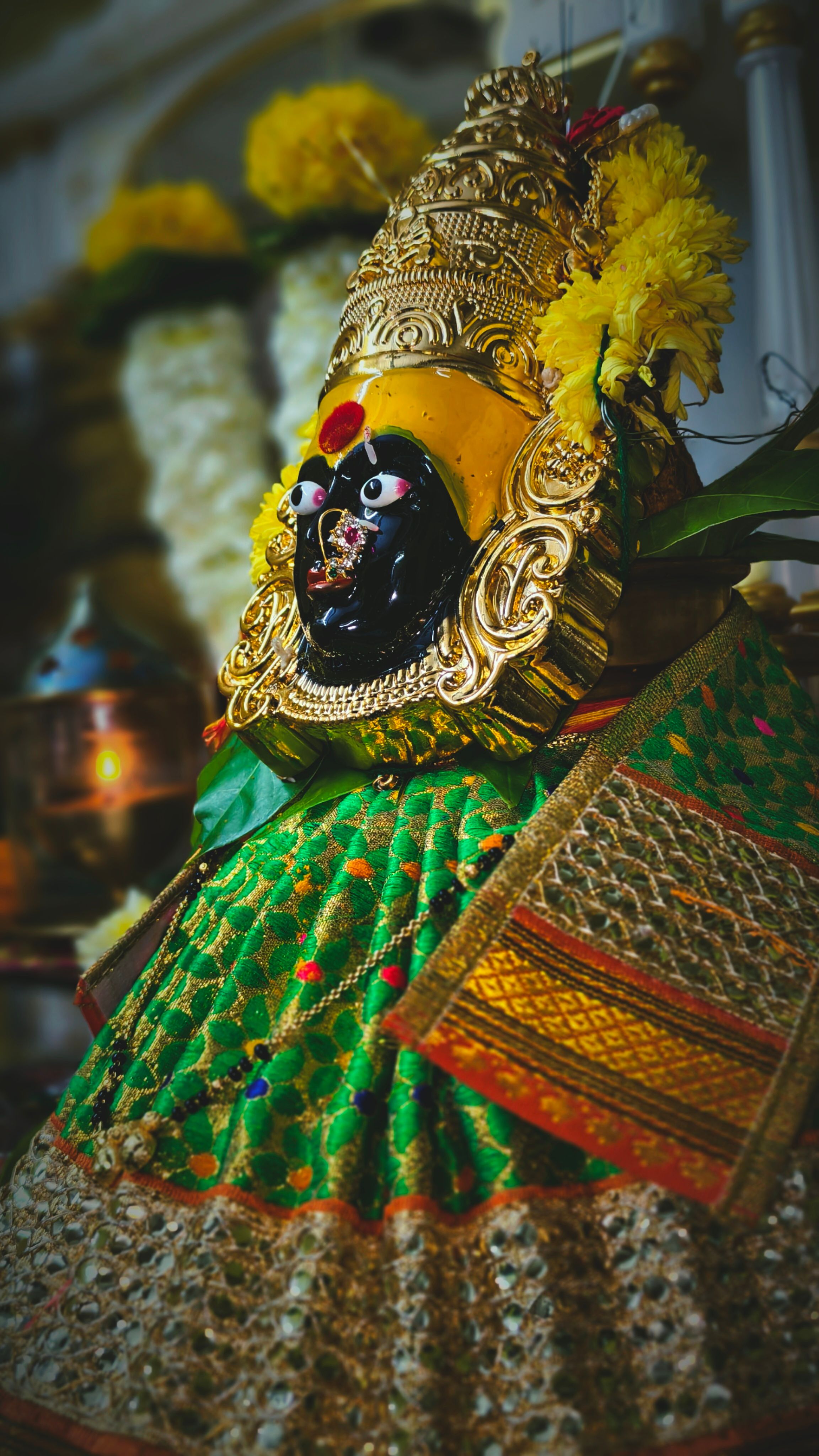 Close-up of a colorful Hindu deity statue adorned with flowers and fabrics representing cultural tradition.