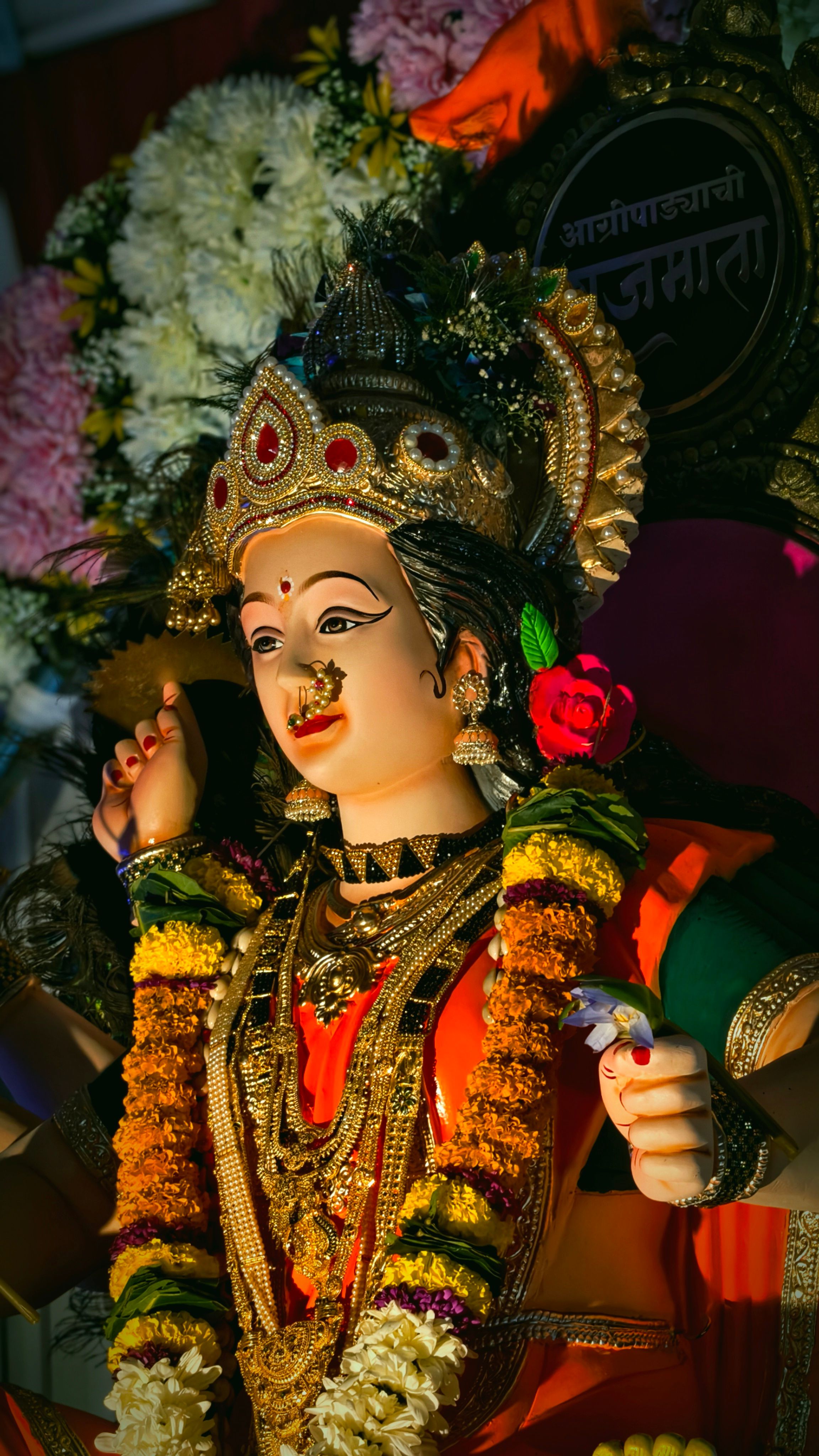 A vivid statue of a goddess adorned with colorful flowers and intricate jewelry, symbolizes spiritual richness.