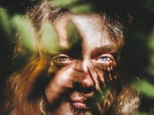 一张女人的脸，蓝色眼睛，在树叶阴影的衬托下，构成了一幅神秘而艺术的肖像