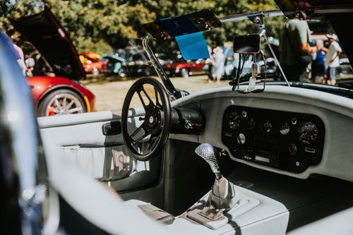 Free Interior view of a vintage car at an outdoor car show, showcasing the classic dashboard and gear shift. Stock Photo