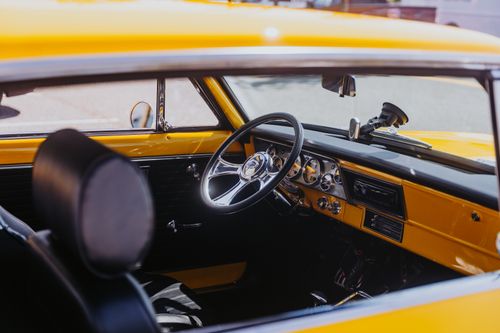 Free Interior of a vintage yellow car showcasing the steering wheel and dashboard details. Stock Photo