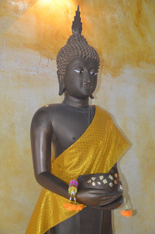 Free A serene statue of Buddha draped in a golden robe, holding a bowl, against a textured background. Stock Photo