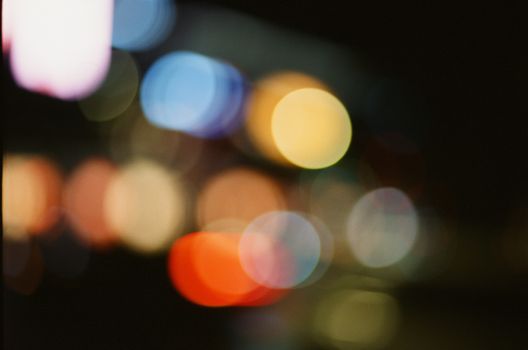 Abstract blurred bokeh lights in a vibrant city at night, showcasing colorful circles.