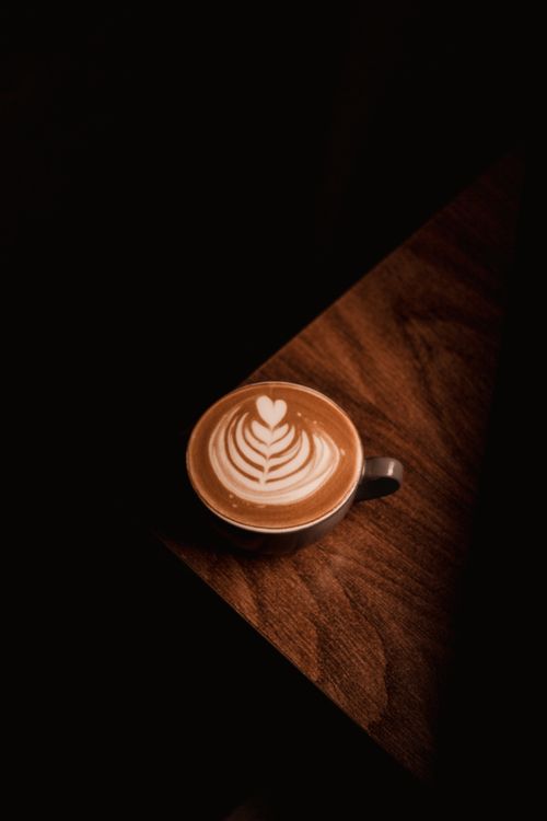 Free A beautifully crafted latte with intricate art on a wooden table, exuding warmth and sophistication. Stock Photo