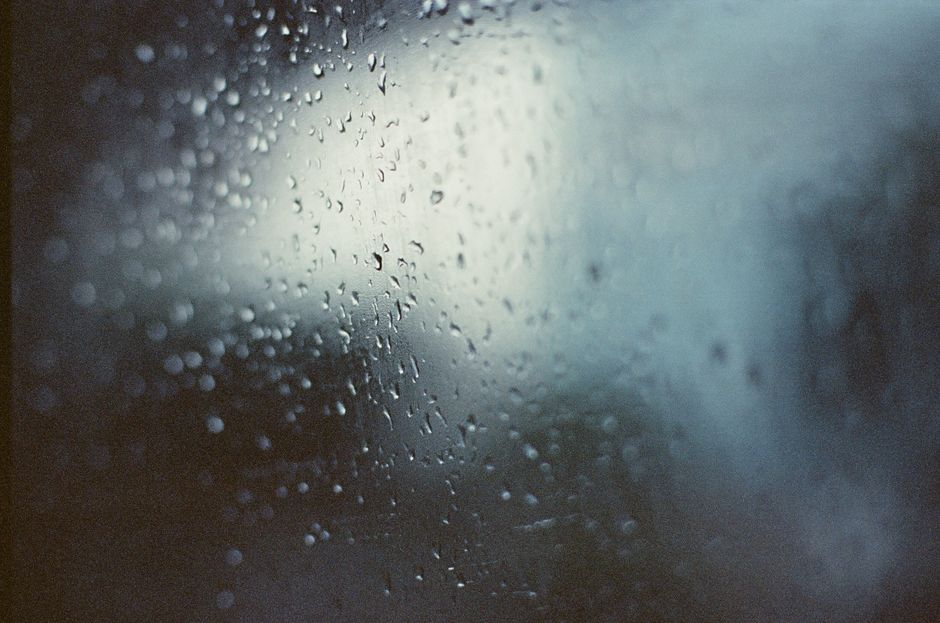 ガラスに映るぼやけた雨粒と、雰囲気のある背景光。ムードのあるテーマに最適です。