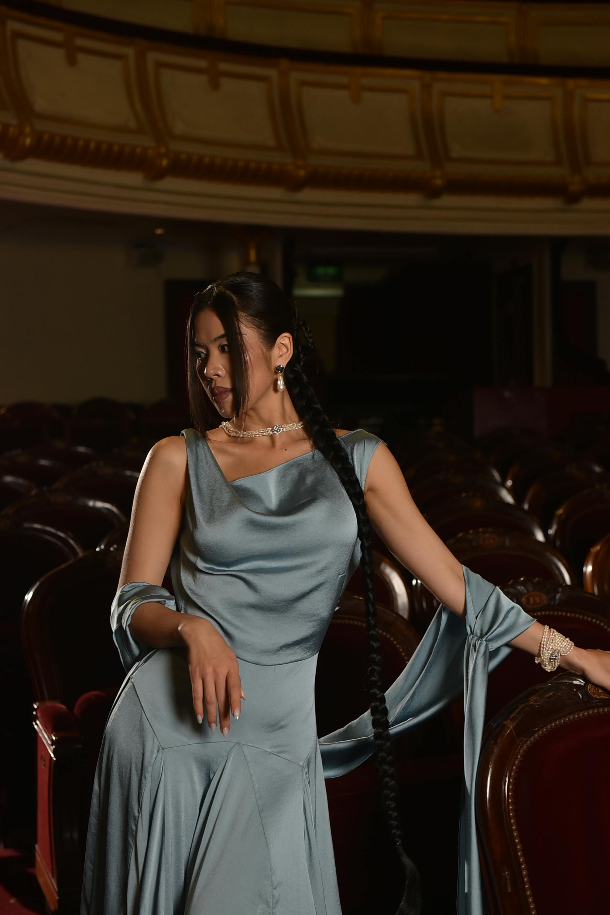 Gratis Donna seduta a teatro con abito di raso, che trasuda eleganza e stile. Foto a disposizione